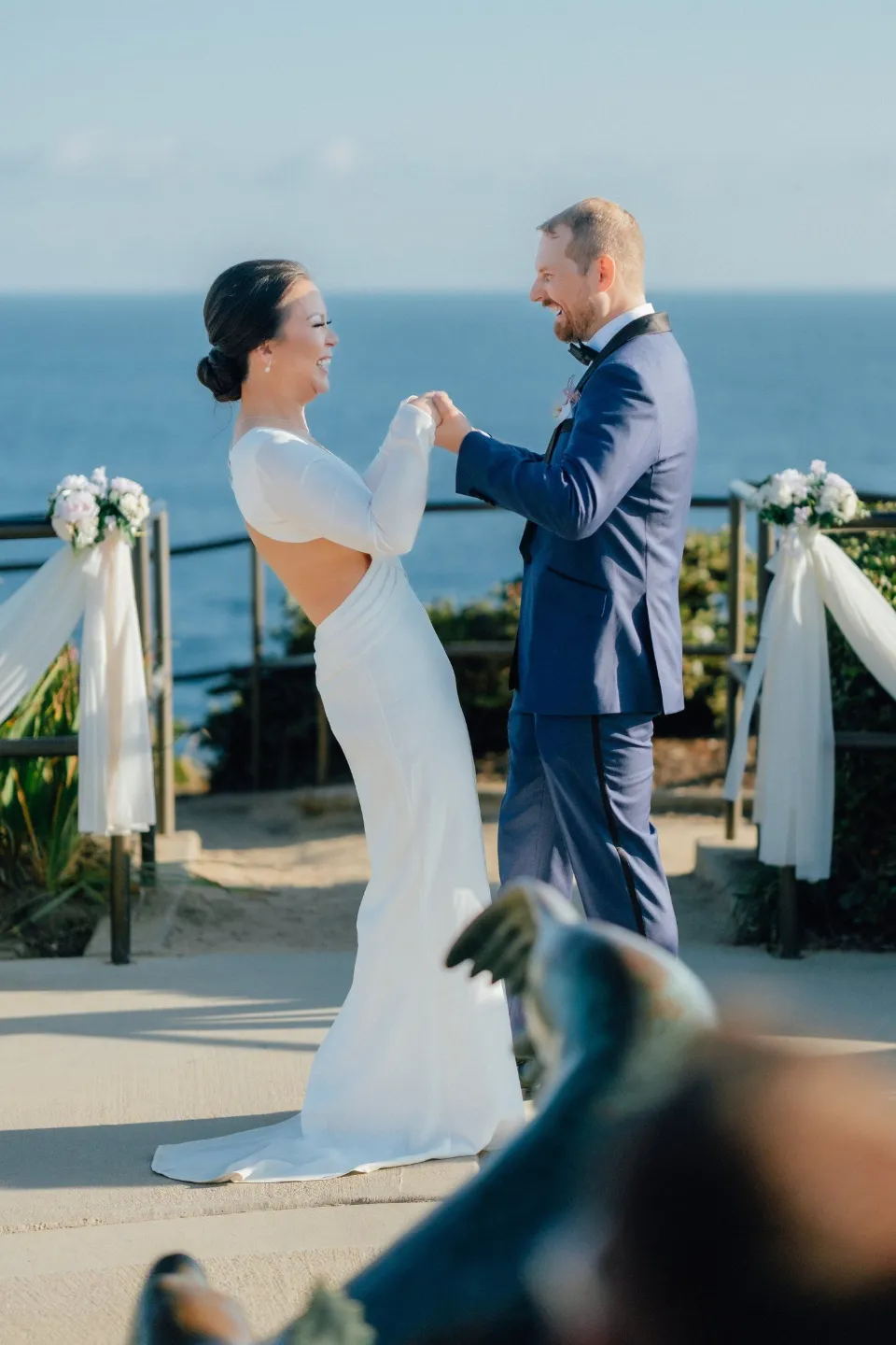 Bride and groom holding hands at an ocean-view ceremony on the bluff