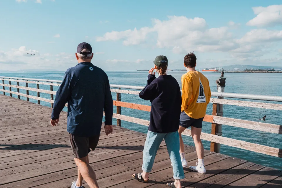 Three men walking along a wooden pier