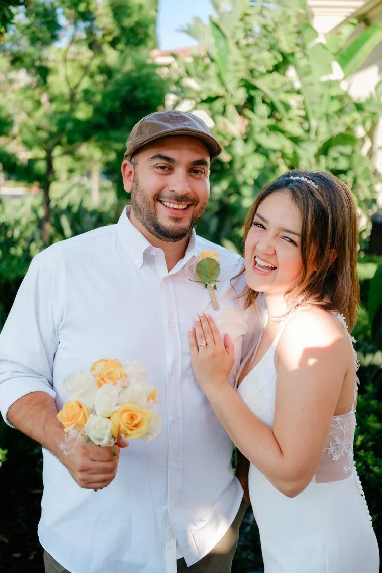 Groom and bride laughing together with a yellow bouquet
