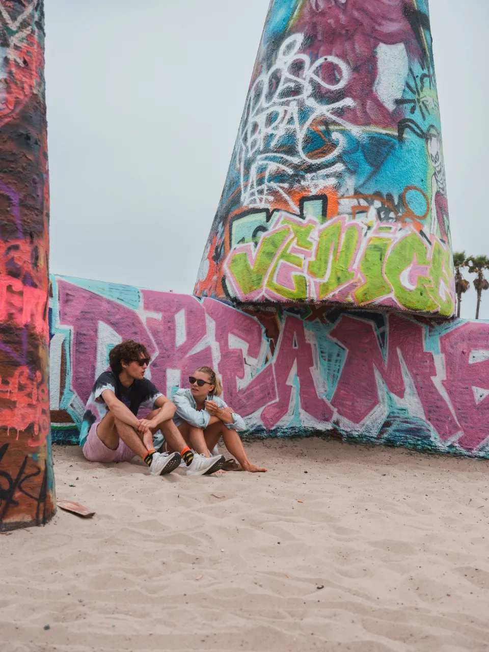 Friends sitting below a graffiti tower on Venice Beach