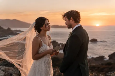 A couple sharing vows on a coastal overlook at sunset