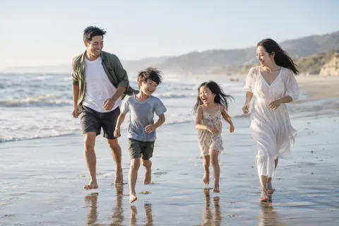 Parents and their two children running along the beach