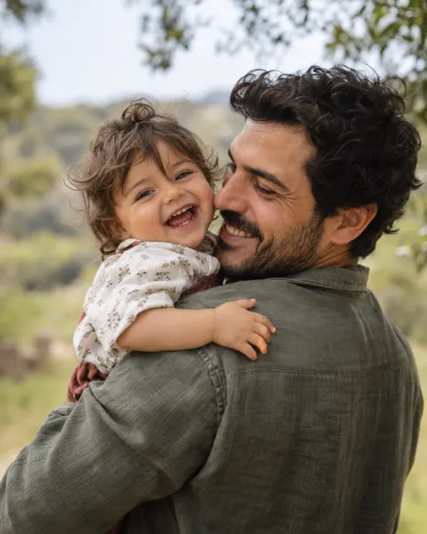 A father holding his laughing toddler on his shoulder